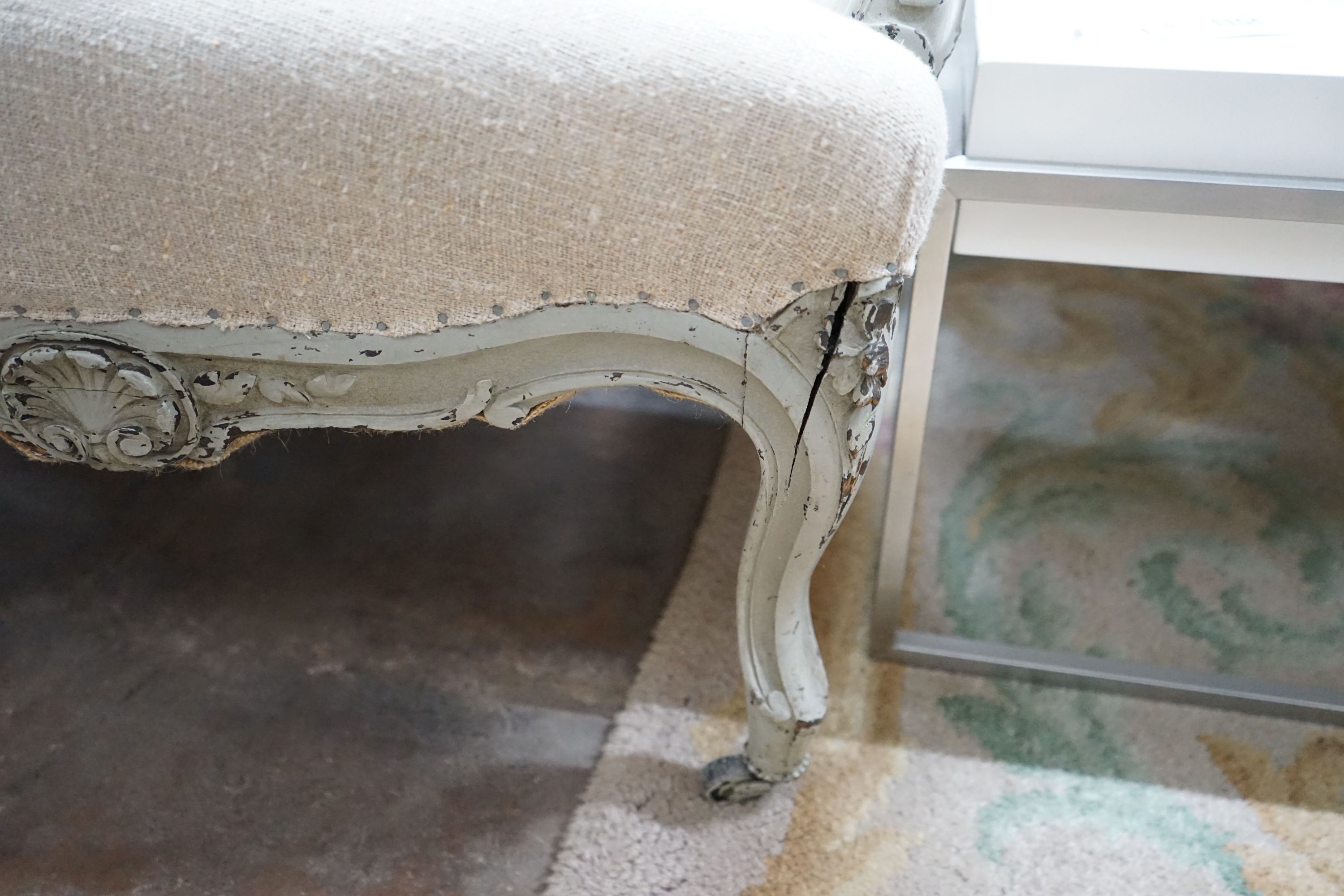 A 19th century French carved wood settee upholstered in a natural linen type fabric, re-painted in grey, length 180cm, depth 60cm, height 102cm